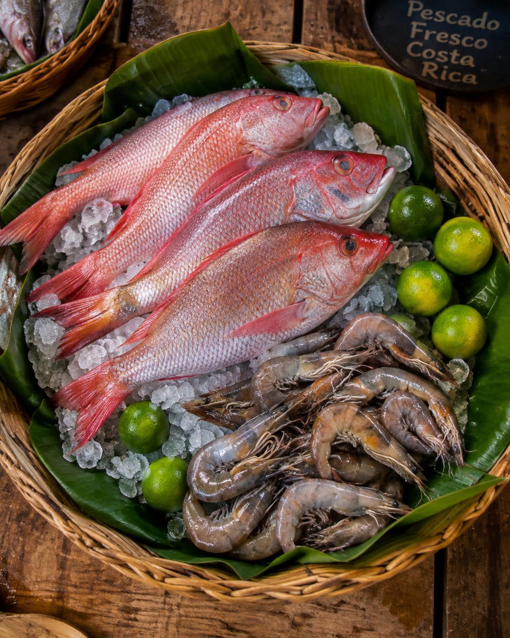 Pargo rojo y camarones sobre hielo en canasta de mimbre